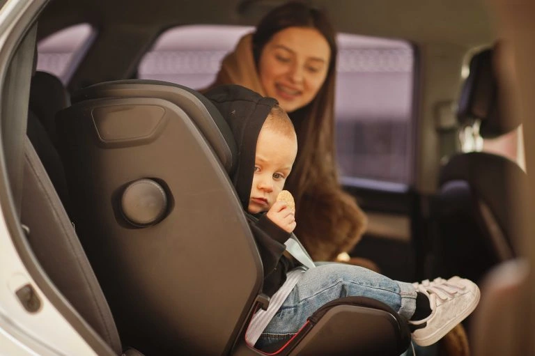 Parent buckling child into baby seat taxi